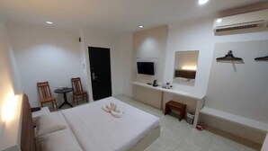 Une chambre d’hôtel équipée d’un lit, d’un bureau, d’une chaise, d’une télévision et d’un appareil de climatisation.