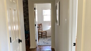 Un pasillo con piso de madera, puertas blancas y un tapete estampado.
