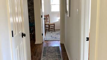 A hallway with wooden flooring, white doors, and a patterned rug.