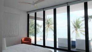 A bedroom with a large bed, a ceiling fan, and a view of the beach through floor-to-ceiling windows. - Viva Villa Sanctuary Ho Tram (Ho Chi Minh City)