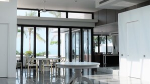 A spacious, modern interior with large windows offering views of palm trees and the ocean. - Viva Villa Sanctuary Ho Tram (Ho Chi Minh City)