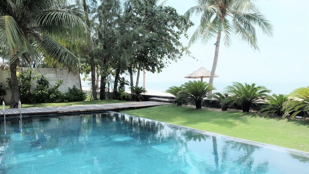 A clear swimming pool surrounded by lush greenery and a view of the sea. - Viva Villa Sanctuary Ho Tram (Ho Chi Minh City)