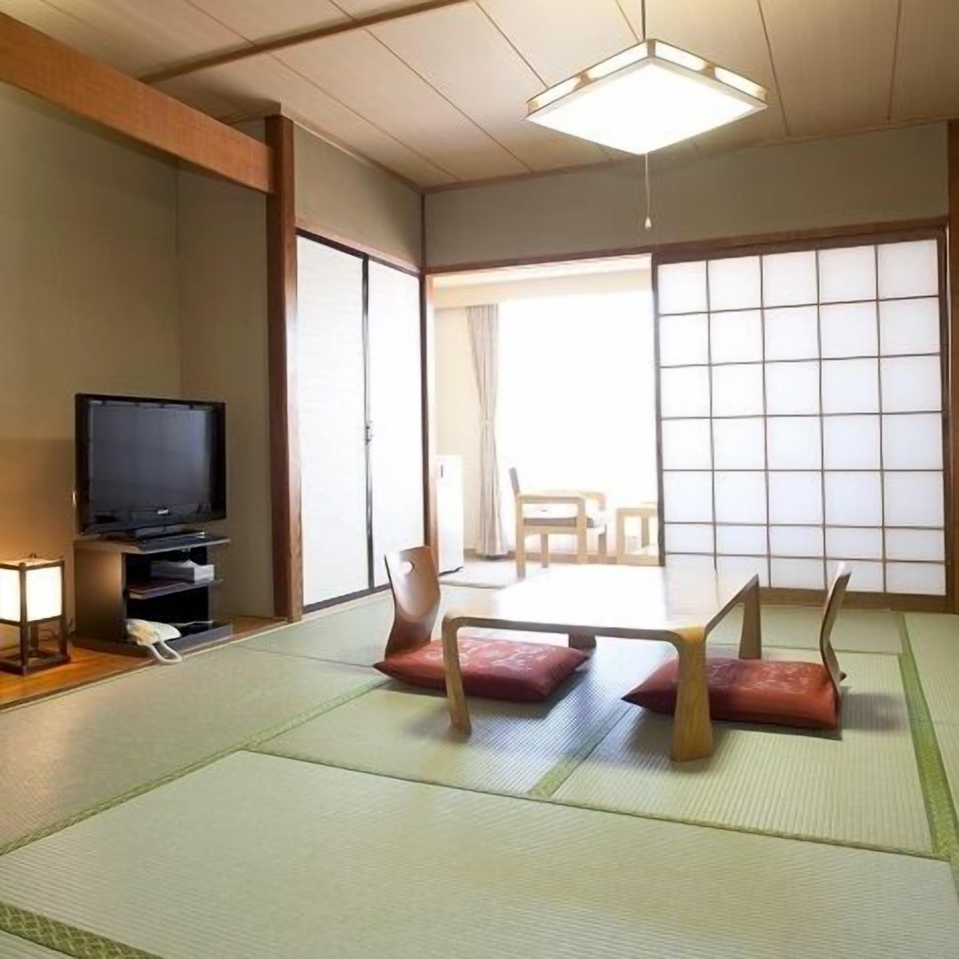 A traditional Japanese room with tatami flooring, a television, and sliding doors.