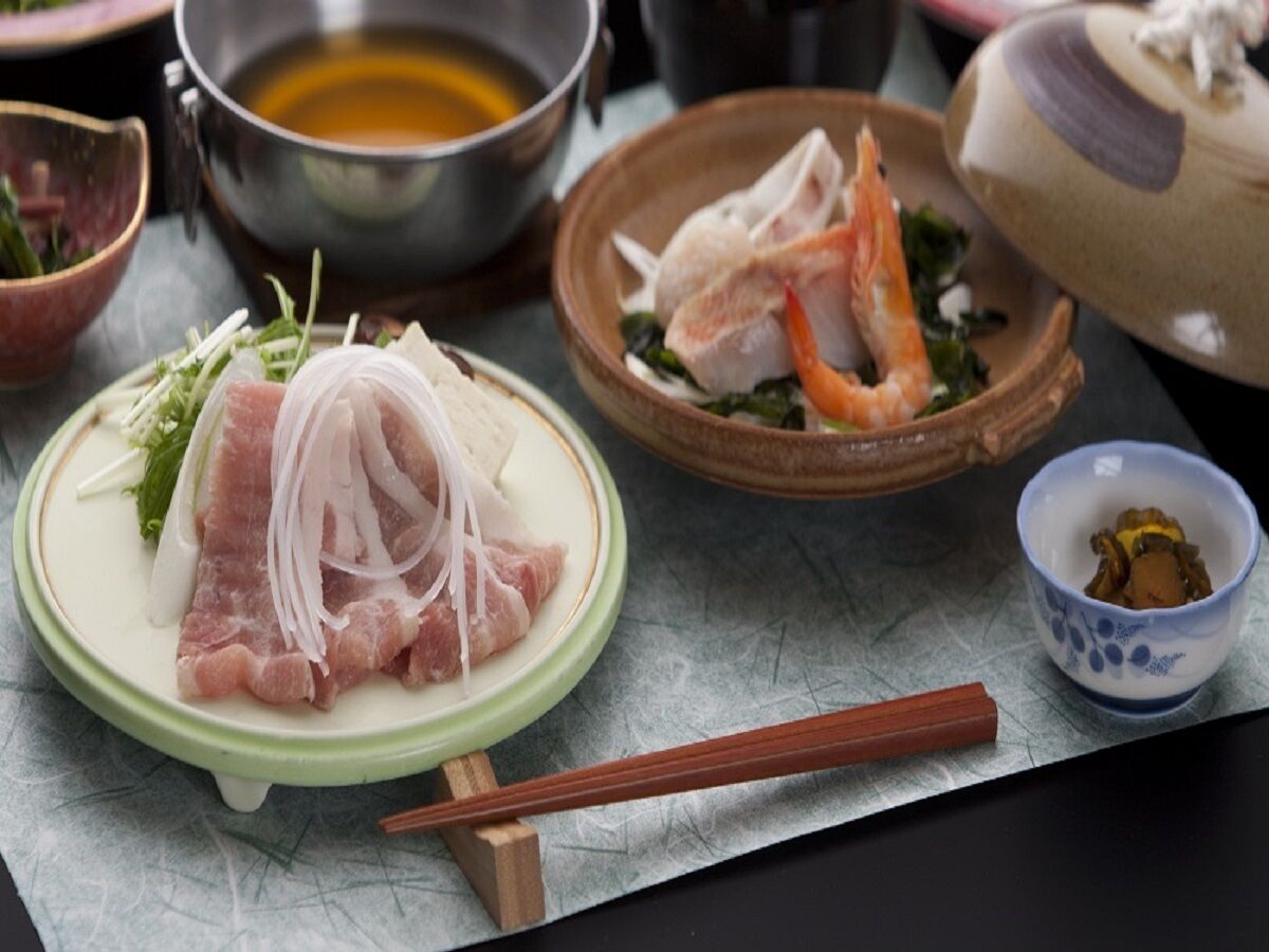 A table with various dishes, including sashimi, a bowl of soup, and a small dish with vegetables.