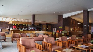 Restaurante com mobiliário de madeira, área de bar e cozinha ao fundo.