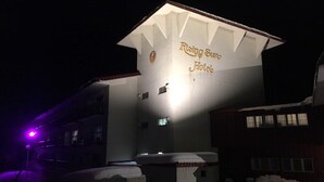 Um hotel com uma placa grande exibindo a inscrição 'Rising Sun Hotel' durante a noite.
