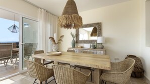 A dining area with a wooden table, wicker chairs, a hanging light fixture, and a large mirror on the wall. - ☀Sun-flooded house / ☀ Panorama sea view & pool (Manilva)
