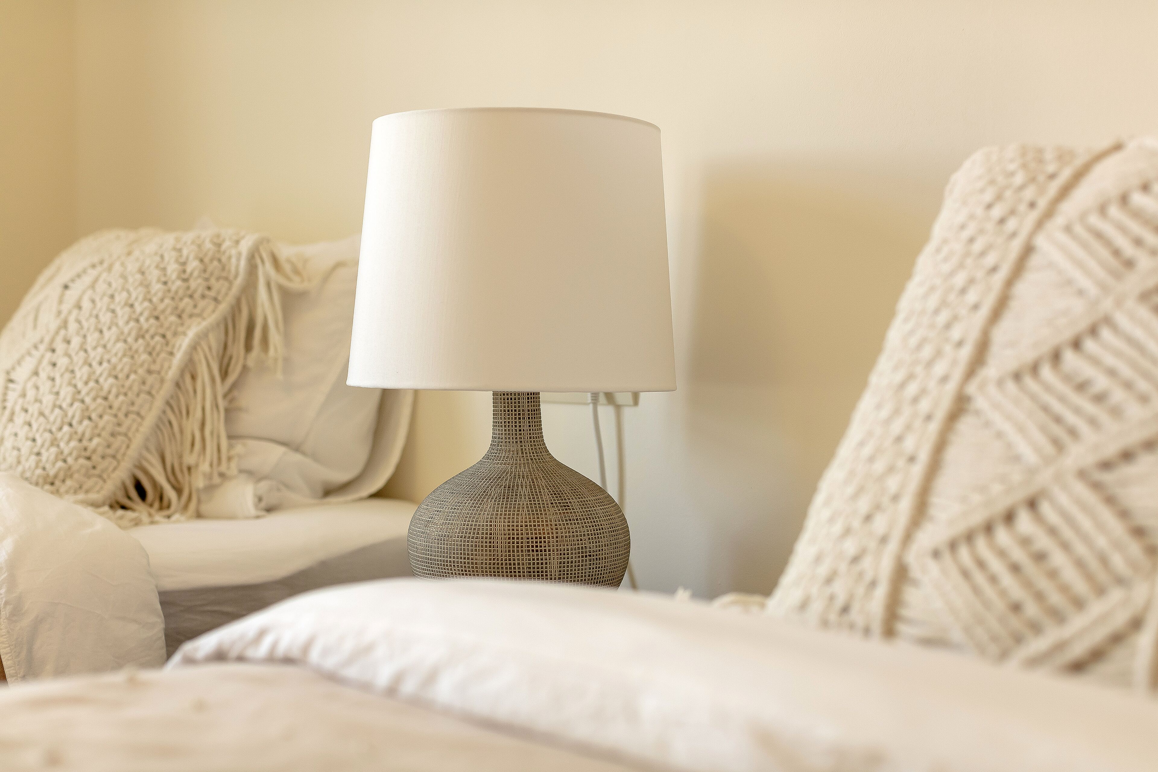 Un lit avec une lampe au design original et un plaid tricoté.