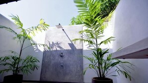 A small, enclosed outdoor space with a concrete door, potted plants, and a tiled floor. - Ayurveda Villa 386 (Balapitiya)