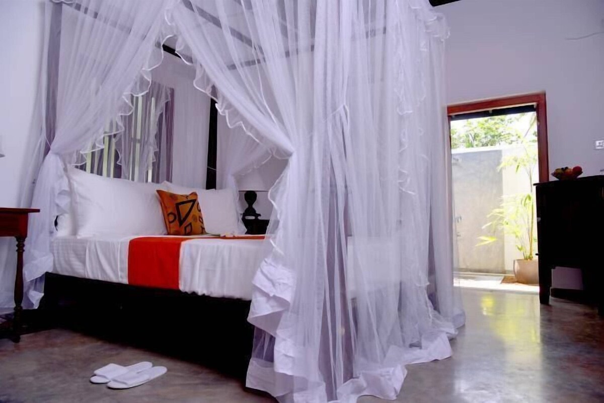 A bedroom with a bed, a bedside table, a chair, and a door leading to an outdoor area.