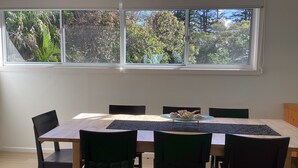 A dining area with a large window, a table, and six chairs. - Bluecrest 2 at Blueys Beach (Blueys Beach)