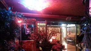 Un espacio interior con mostrador de recepción, plantas en macetas y puerta de vidrio.