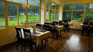 A dining area with large windows, wooden flooring, and tables set for dining.
