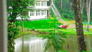 A view of a building surrounded by lush greenery and a body of water.