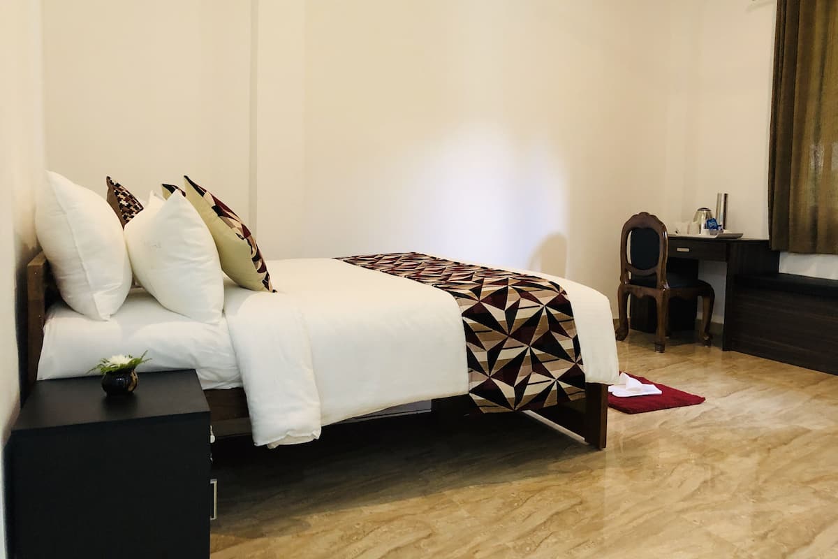 Un dormitorio ordenado con cama, mesita de noche y escritorio.