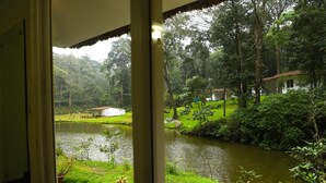 A view of a river with a house and lush greenery in the background.