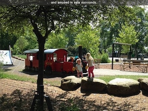 Explore a scenic park setting with a miniature train, surrounded by large rocks and lush trees.
