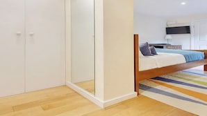 A bedroom with a bed, a wardrobe, and a mirror.