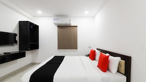 A modern hotel room with a bed, a flat-screen TV, a wardrobe, and a built-in air conditioning unit. - Capital O 63727 Mythri Hotel (Hyderabad)