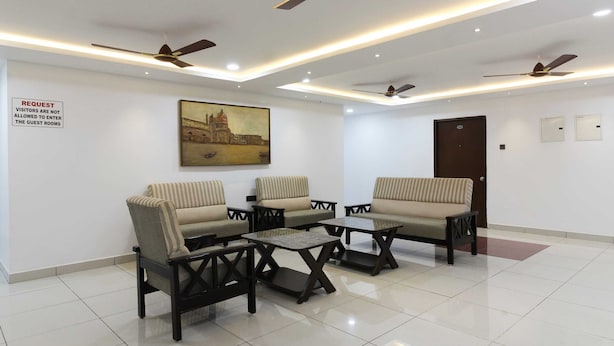A hotel lobby with sofas, tables, ceiling fans, and a painting on the wall. - Capital O 63727 Mythri Hotel (Hyderabad)