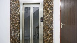 Un ascenseur doté d’un écran numérique affichant le chiffre 4, entouré d’un mur dont le motif ressemble à du marbre.
