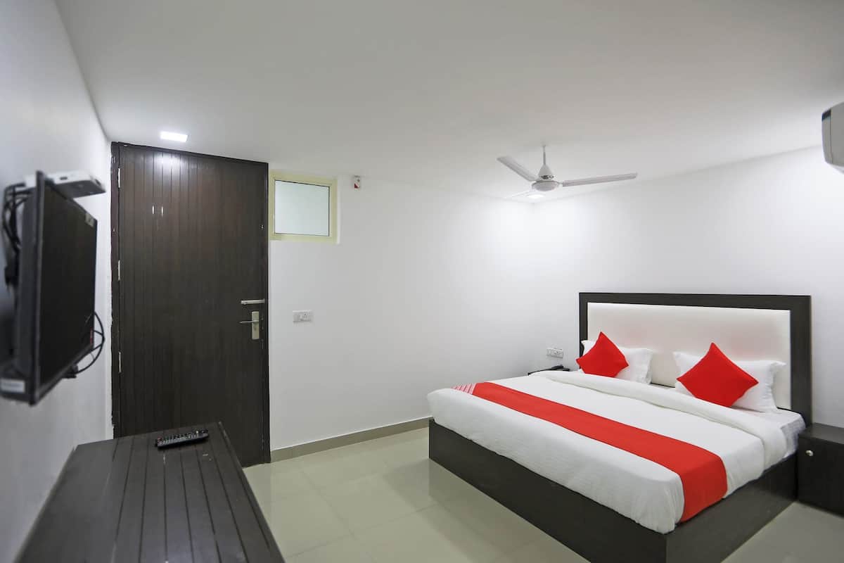 A bedroom with a bed, a ceiling fan, a TV mounted on the wall, and a wooden bench.