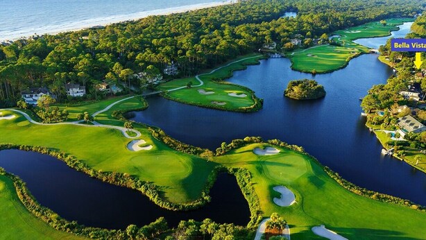 Un campo de golf con obstáculos acuáticos, rodeado de árboles densos y una masa de agua.
