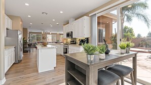 A spacious kitchen with a central island, white cabinetry, and a view of the outdoors.