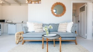 A modern living room with a grey sofa, a round coffee table, and a decorative mirror on the wall.