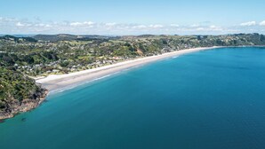 An aerial view of a coastal area with a beach, residential buildings, and a hilly landscape.