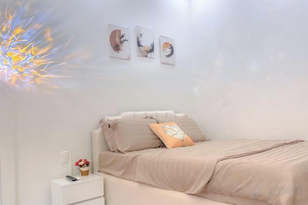 A bedroom with a bed, bedside table, and wall art.