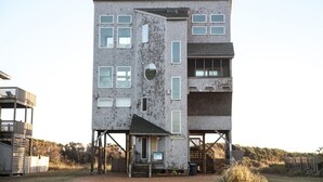 A multi-story building with a unique architectural design, featuring a combination of brick and glass elements, and a small entrance with steps.