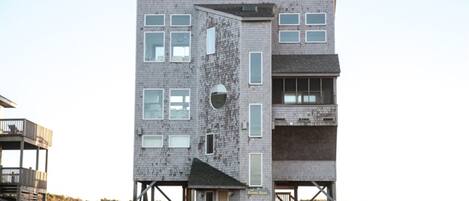 Un immeuble à plusieurs étages doté d’une architecture originale, caractérisé par une combinaison d’éléments en brique et en verre, et une petite entrée avec des marches.