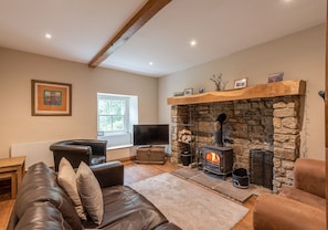 A cozy living room with a stone fireplace, leather sofa, and a television.