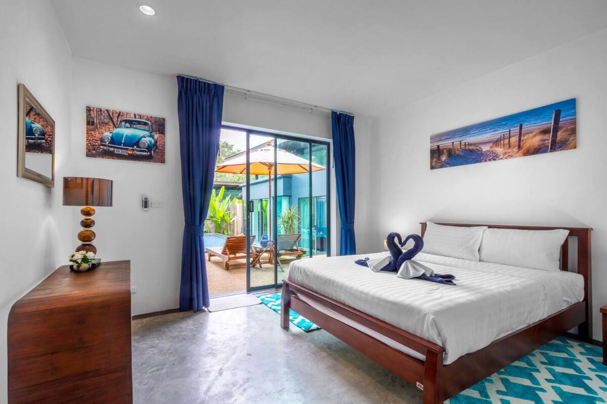 Ein Hotelzimmer mit Bett, einem Holzkapmierer, einem Schreibtisch und Blick ins Freie.