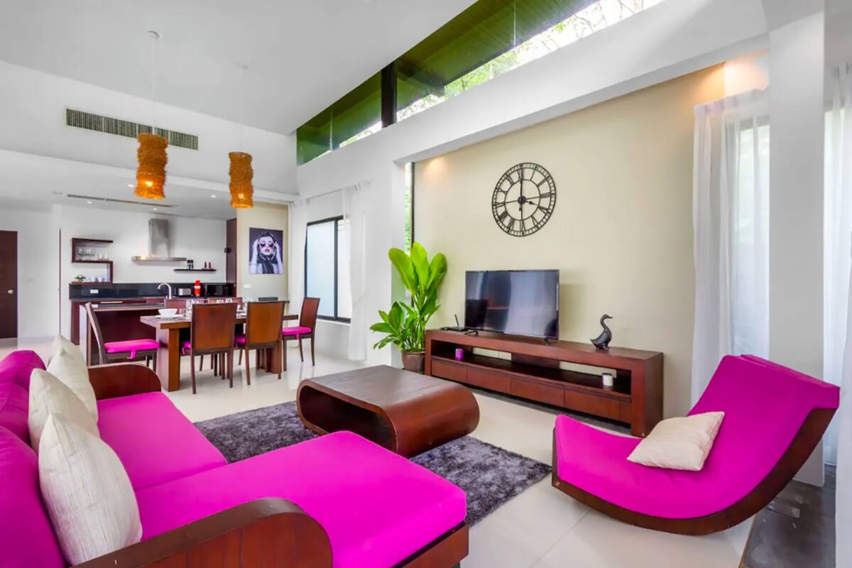 Ein modernes Wohnzimmer mit einer Couch, einem Couchtisch und einem Fernseher. Es gibt eine Essecke mit Stühlen und einem Tisch.