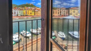 A balcony with a view of a harbor, boats, and colorful buildings across the water.