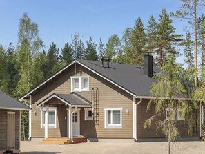 Une maison à deux étages, avec un toit à pignon, une cheminée et un porche à l’avant.