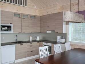 A modern kitchen with wooden cabinets, a built-in microwave, a sink, and a dining area with a table and chairs.