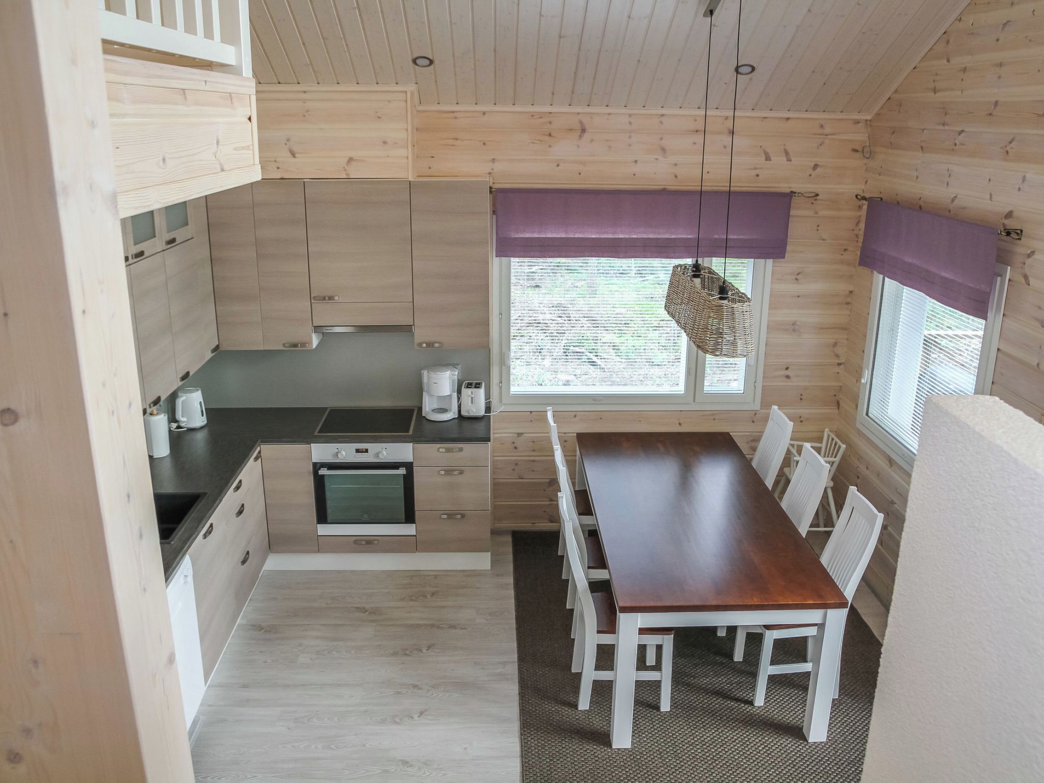 Une cuisine compacte avec un coin repas, des murs en bois et une fenêtre donnant sur un beau paysage.