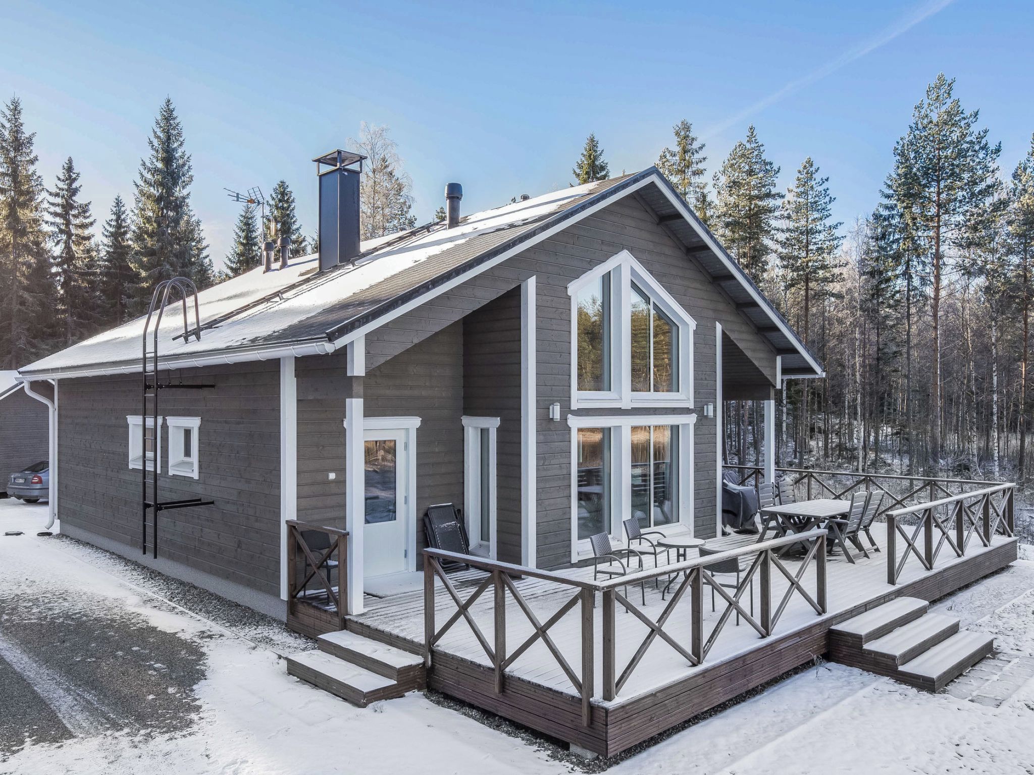 A cabin with a deck, a covered outdoor seating area, and a large window.