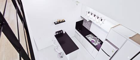 A modern kitchen with white cabinetry, a black countertop, and a built-in sink.