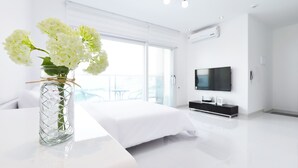 A modern hotel room with a large bed, a TV, and a balcony with a view. - Glories Pension (Buan)