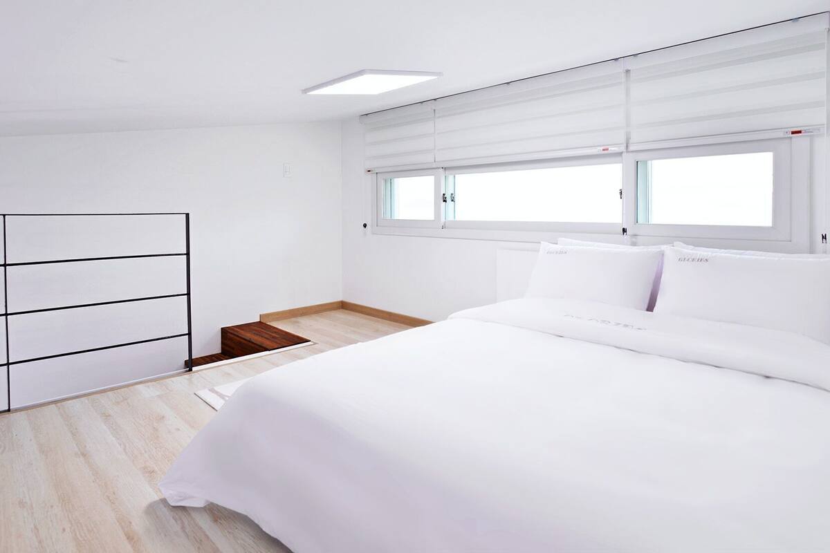 A bedroom with a bed, a wardrobe, and a window with blinds.