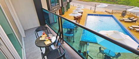 A balcony with a pool, outdoor seating, and a view of the road.