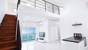 A modern interior with a wooden staircase, a flat-screen TV, a small kitchen area, and a balcony with a view. - Glories Pension (Buan)