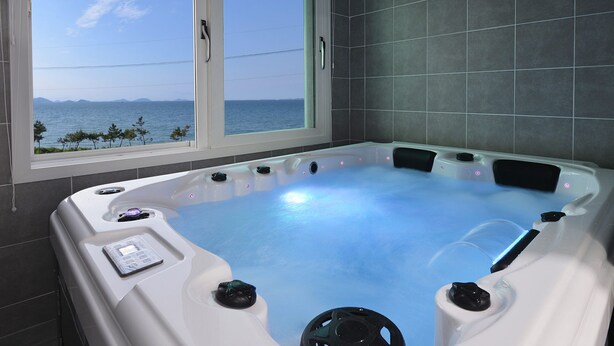 A hot tub with a view of the sea, a window, and a control panel. - Glories Pension (Buan)