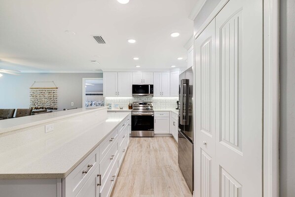 A modern kitchen with white cabinetry, stainless steel appliances, and a light wood floor.