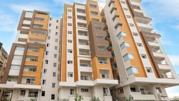 Un edificio residencial de varios pisos con balcones, un diseño arquitectónico moderno y un cielo despejado al fondo.