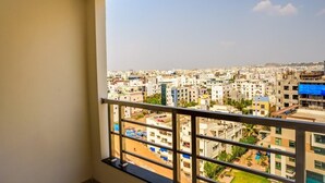 Un balcón con vistas a una zona urbana densamente poblada, con diversos edificios y un cielo despejado.